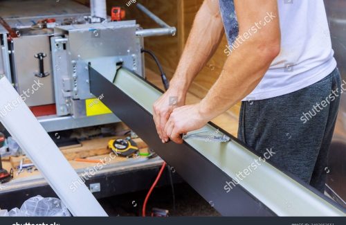 stock-photo-installing-hidden-gutter-hangers-using-pre-inserted-screw-to-attach-new-gutters-to-roof-2493952551